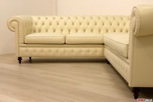 Divano angolare chesterfield panna con piedi alti in legno