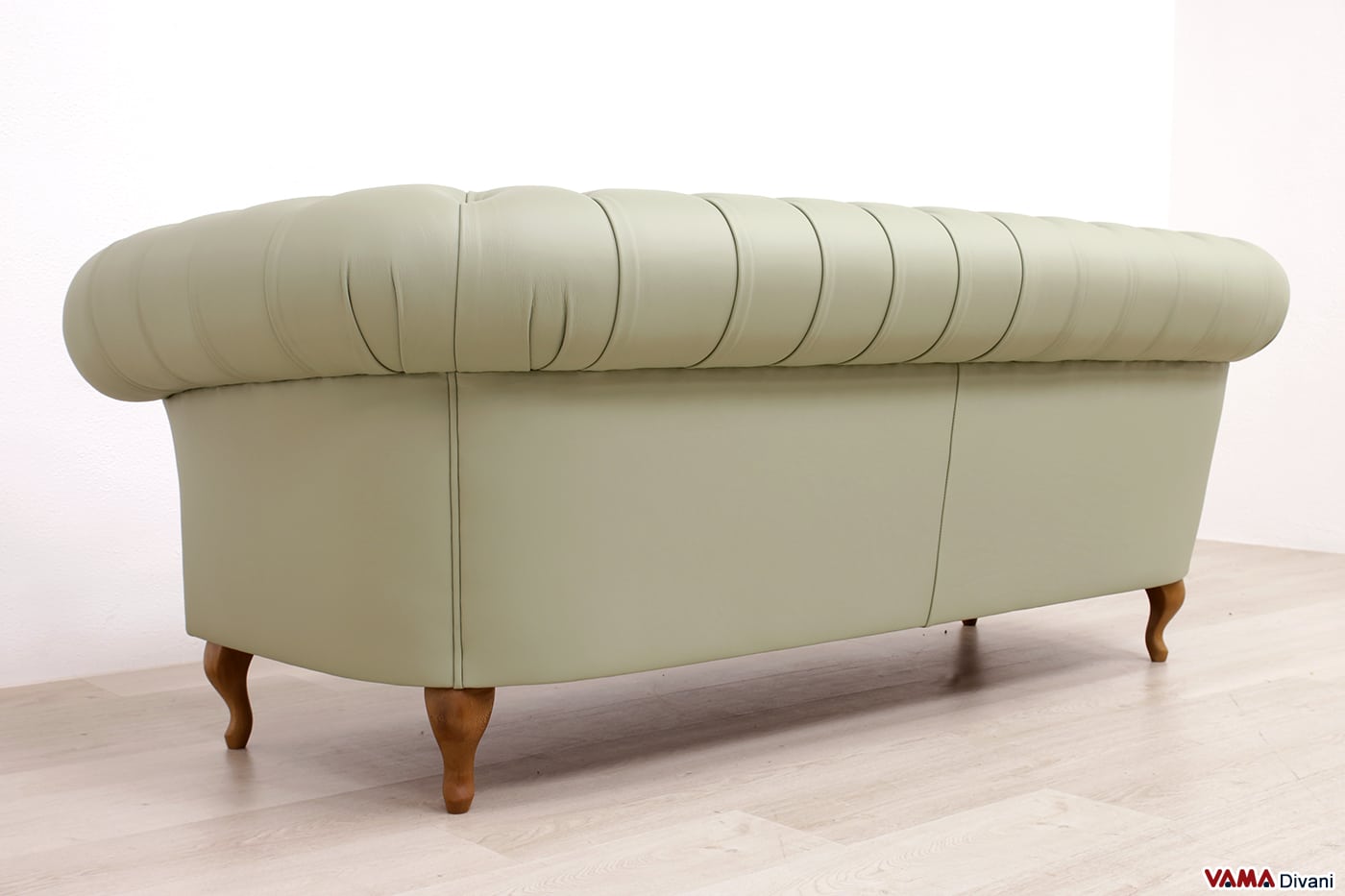 Vista posteriore del divano Chesterfield verde salvia con finitura liscia e piedini in legno