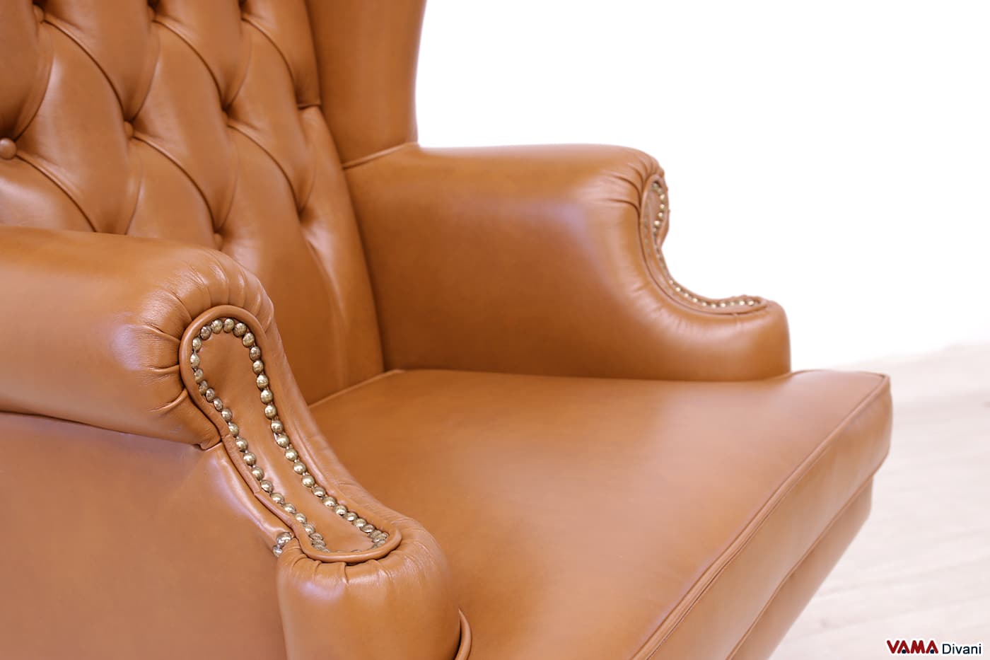 Dettaglio bracciolo poltrona ufficio in pelle marrone cognac con borchie in ottone