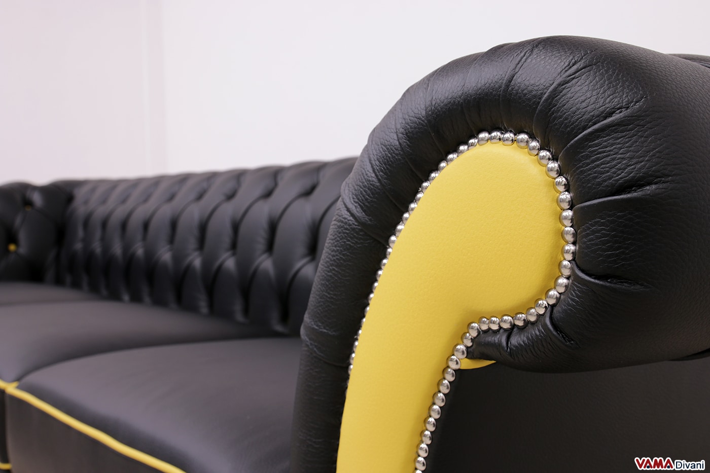 Dettaglio dei braccioli del divano Chesterfield in pelle nera e gialla, con chiodatura decorativa personalizzabile