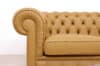 Dettaglio del bracciolo rotondo plissettato e dello schienale capitonné di un divano Chesterfield 2 posti color cuoio miele