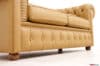 Dettaglio della fascia frontale capitonné con bottoni rivestiti e piedino a cipolla in legno color noce del divano Chesterfield 2 posti