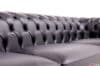 Dettaglio ravvicinato dello schienale capitonné di un divano Chesterfield in pelle nera, con bottoni rivestiti in pelle.