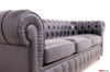 Dettaglio del bracciolo sinistro di un divano Chesterfield in pelle nera, con finiture artigianali in evidenza.